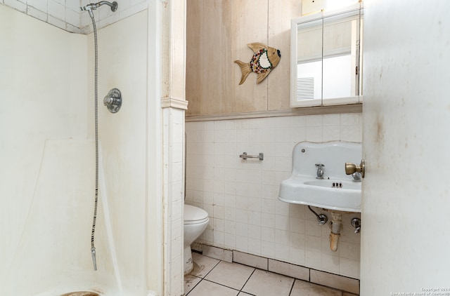 bathroom with tile patterned floors, toilet, sink, and tile walls