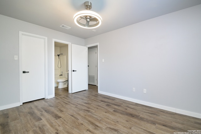 unfurnished bedroom with wood-type flooring and ensuite bathroom