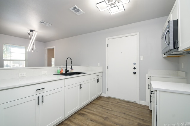 kitchen featuring kitchen peninsula, dark hardwood / wood-style floors, white cabinetry, and sink