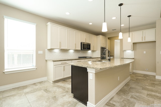 kitchen featuring white cabinetry, hanging light fixtures, light stone counters, a kitchen island with sink, and appliances with stainless steel finishes