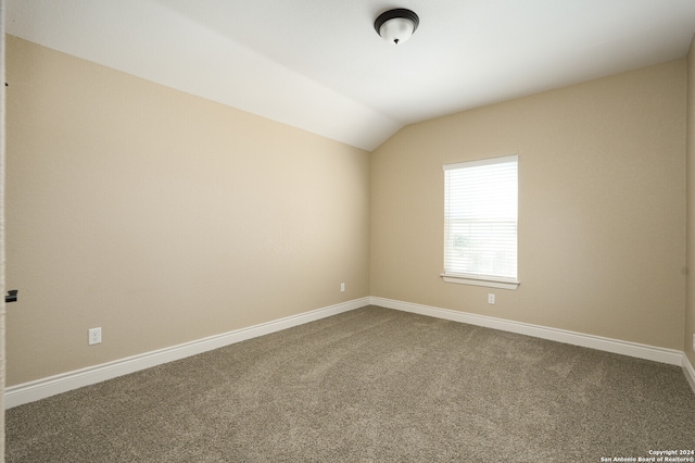 carpeted empty room with vaulted ceiling