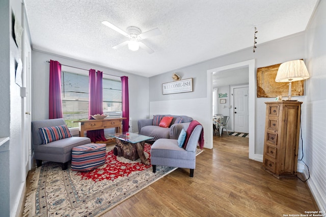 living room featuring ceiling fan, wood-type flooring, and a textured ceiling