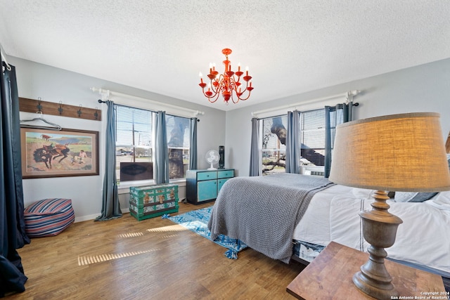 bedroom featuring a textured ceiling, hardwood / wood-style flooring, and an inviting chandelier