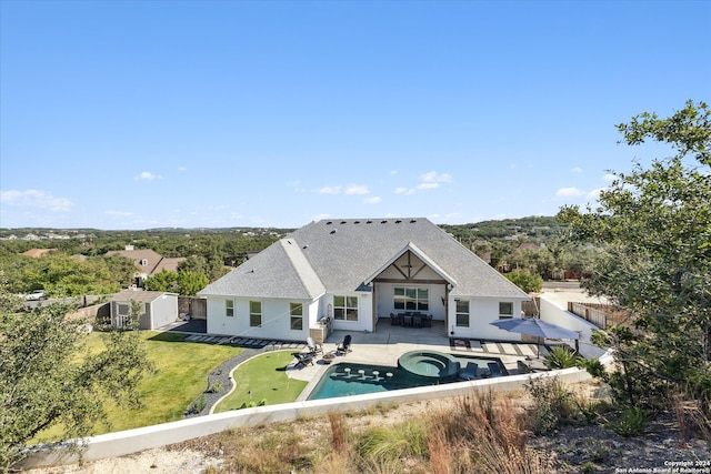 rear view of house with a patio area, a swimming pool with hot tub, and a shed