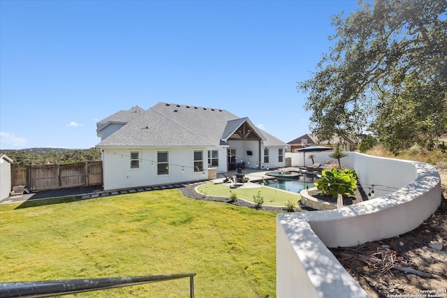 rear view of house featuring a lawn, a patio, and a fenced in pool