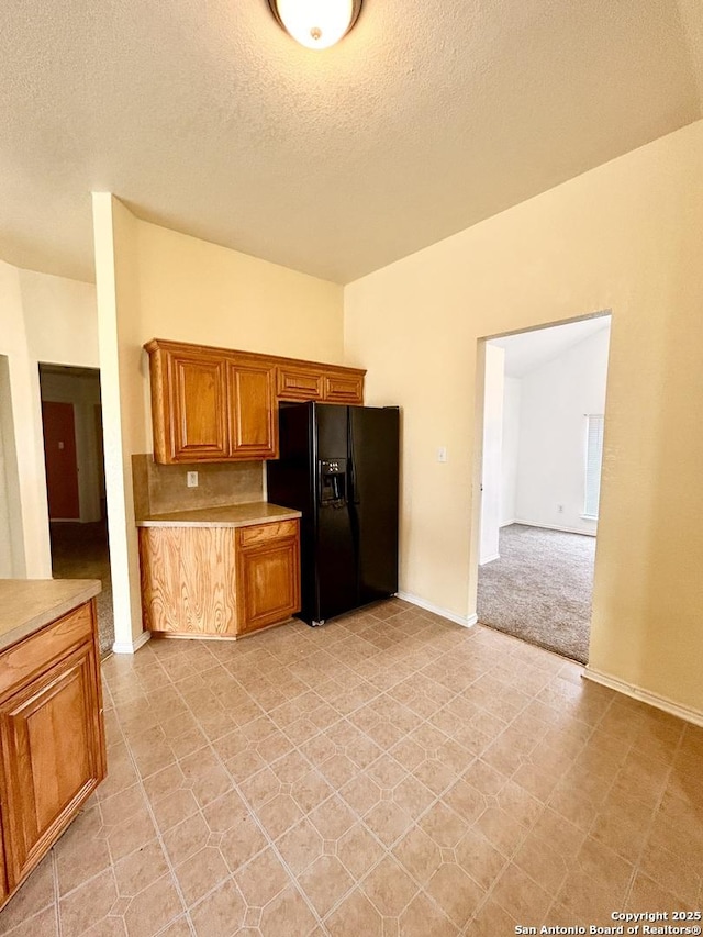 6050 Lakefront, San Antonio, TX 78222 - kitchen with black fridge, light countertops, brown cabinets, a textured ceiling, and baseboards
