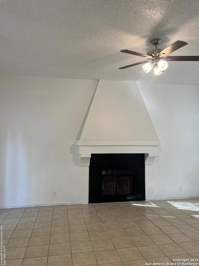 room details with ceiling fan, a fireplace, a textured ceiling, and tile patterned flooring