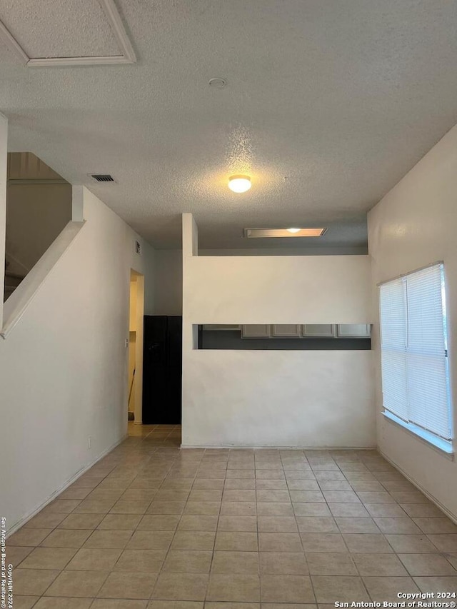 tiled empty room featuring a textured ceiling