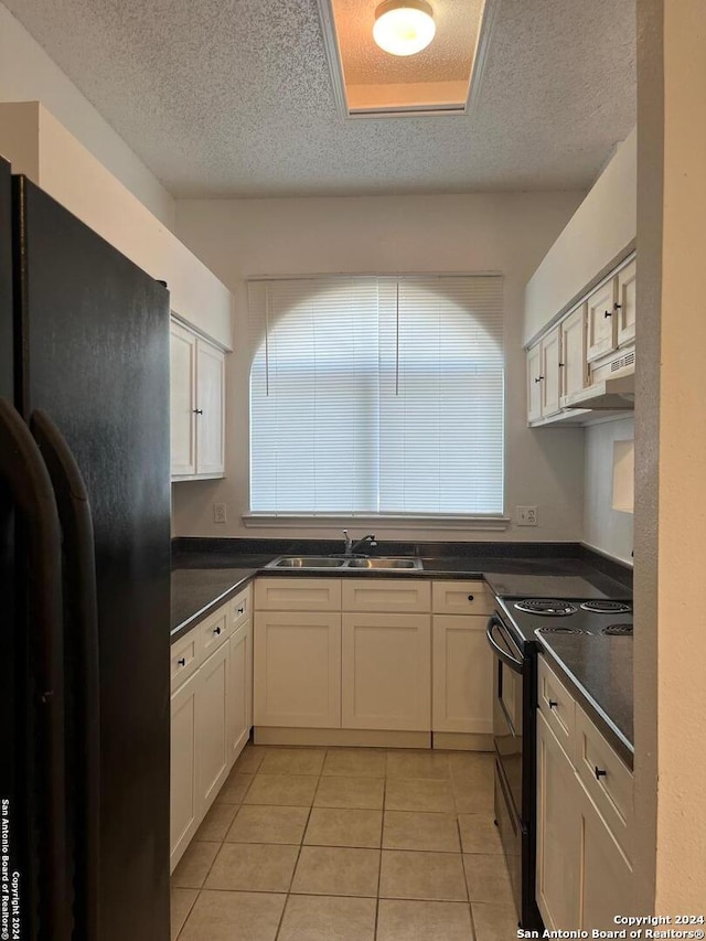 kitchen featuring sink, light tile patterned floors, black appliances, and a textured ceiling