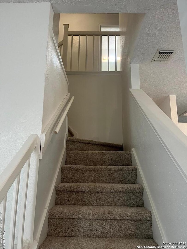 stairs featuring a textured ceiling