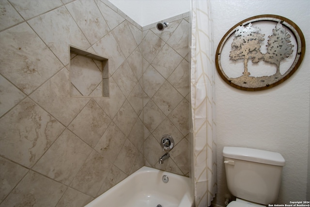 bathroom with tiled shower / bath combo and toilet