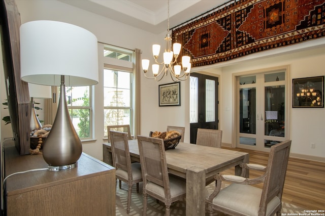 dining space with ornamental molding, wood-type flooring, and an inviting chandelier