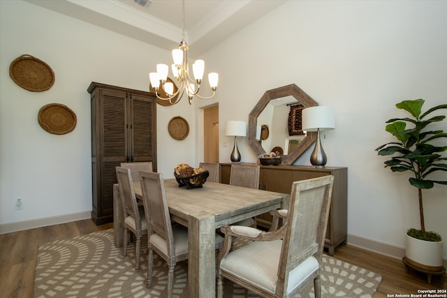 dining space with dark hardwood / wood-style flooring, ornamental molding, and a notable chandelier