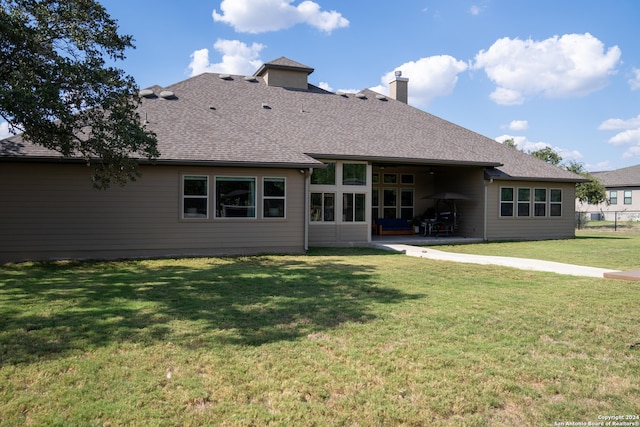 rear view of property featuring a lawn and a patio