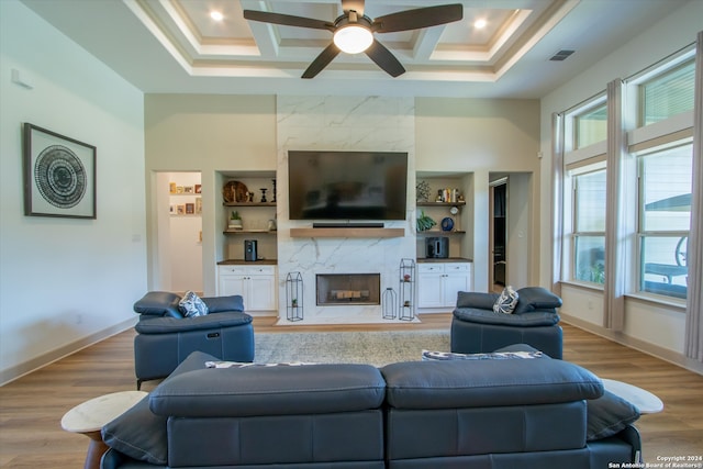 living room featuring a fireplace, light hardwood / wood-style flooring, built in features, and coffered ceiling