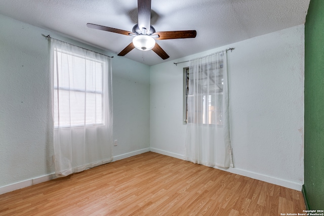 unfurnished room with a textured ceiling, light wood-type flooring, and ceiling fan