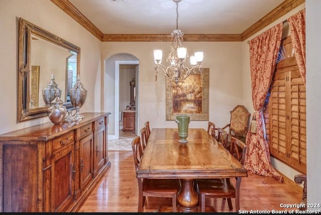 dining area with light wood-type flooring, ornamental molding, and a notable chandelier