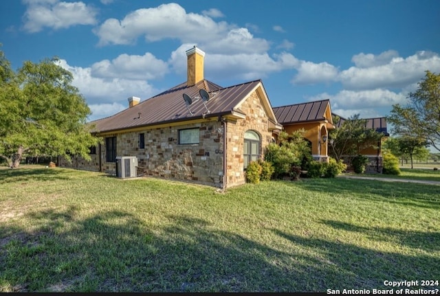 back of property with a lawn and central AC