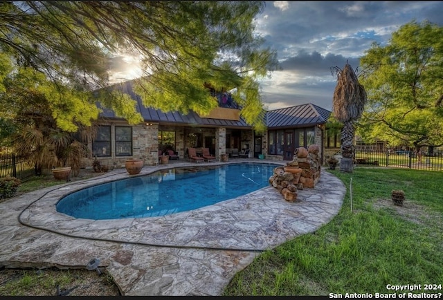 pool at dusk featuring a yard