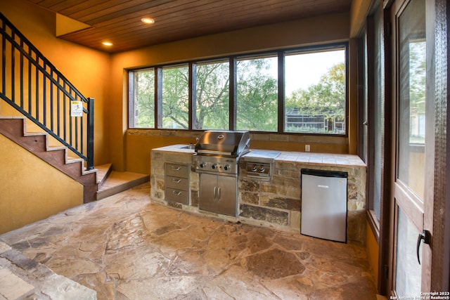 interior space with stainless steel fridge, tile counters, and wood ceiling