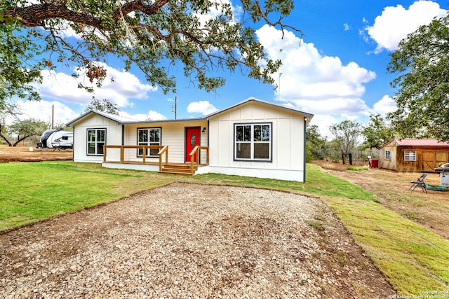 view of front of property featuring covered porch, a front yard, and a storage shed