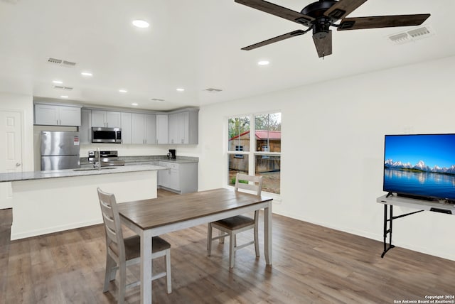 dining area featuring ceiling fan, sink, and wood-type flooring