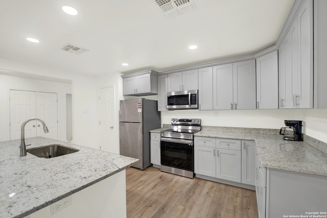 kitchen featuring light stone counters, sink, light wood-type flooring, and stainless steel appliances