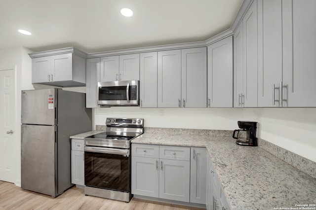 kitchen with light stone counters, stainless steel appliances, and light wood-type flooring