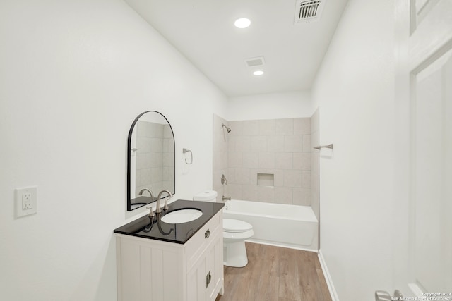 full bathroom with hardwood / wood-style flooring, vanity, toilet, and tiled shower / bath