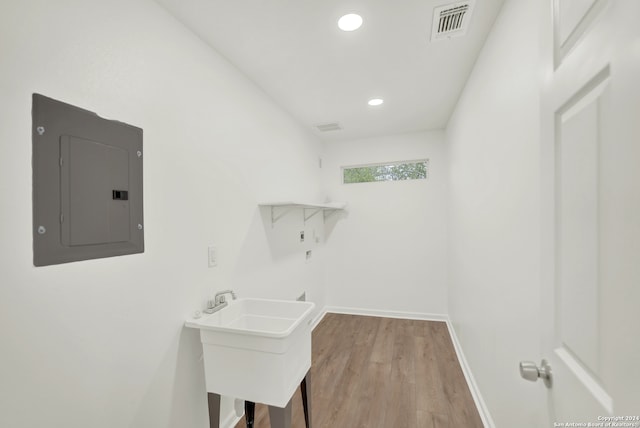 laundry room with washer hookup, light hardwood / wood-style floors, sink, and electric panel