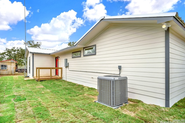 back of house featuring a shed, a yard, and central AC