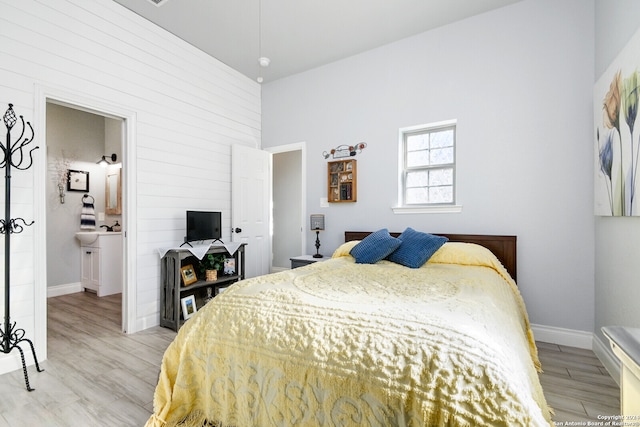 bedroom with connected bathroom and light hardwood / wood-style flooring