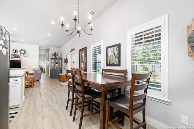 dining space featuring lofted ceiling, light hardwood / wood-style flooring, and an inviting chandelier