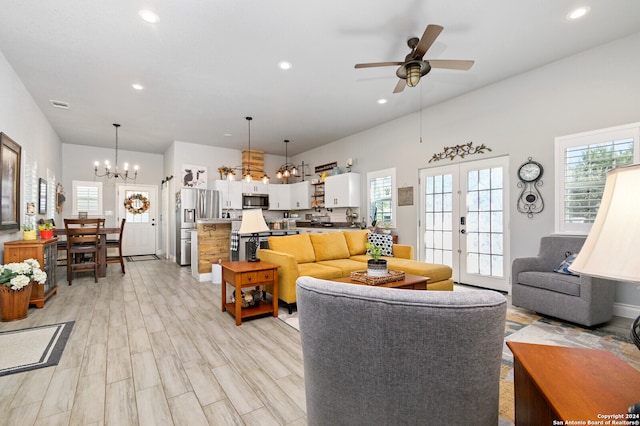 living room with ceiling fan with notable chandelier, light hardwood / wood-style flooring, and french doors