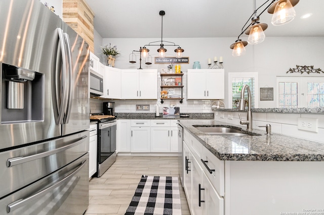 kitchen featuring sink, white cabinetry, decorative light fixtures, dark stone counters, and stainless steel appliances