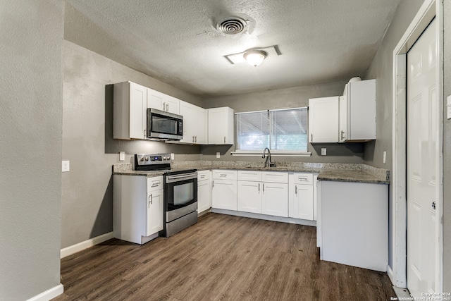 kitchen featuring white cabinetry, dark wood-type flooring, dark stone counters, a textured ceiling, and appliances with stainless steel finishes