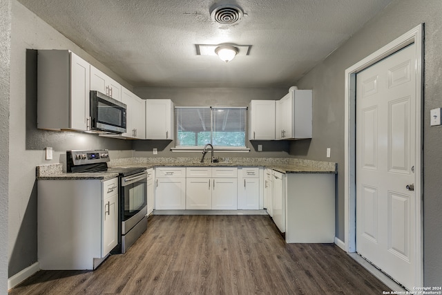 kitchen with a textured ceiling, white cabinetry, stainless steel appliances, and dark wood-type flooring