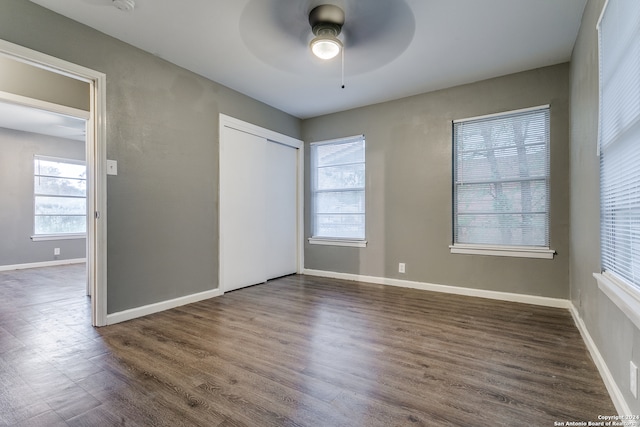 unfurnished bedroom with dark hardwood / wood-style floors, ceiling fan, a closet, and multiple windows