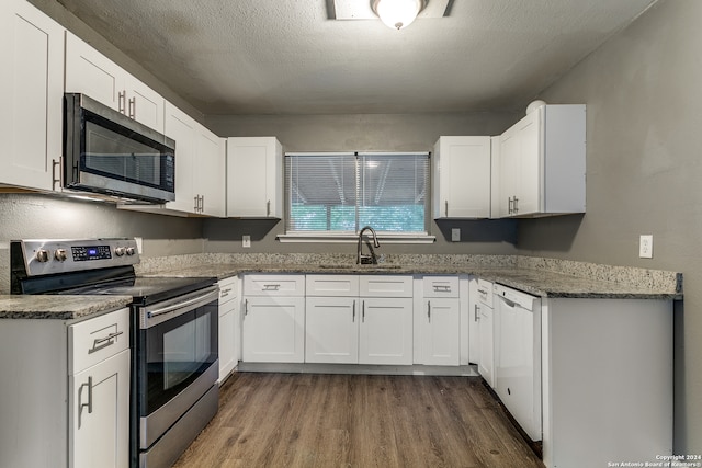 kitchen with a textured ceiling, white cabinets, dark hardwood / wood-style floors, and appliances with stainless steel finishes