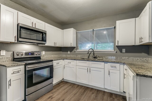 kitchen featuring dark wood-type flooring, sink, white cabinets, and stainless steel appliances