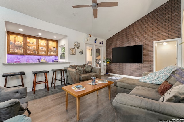 living room with french doors, brick wall, ceiling fan, hardwood / wood-style flooring, and high vaulted ceiling