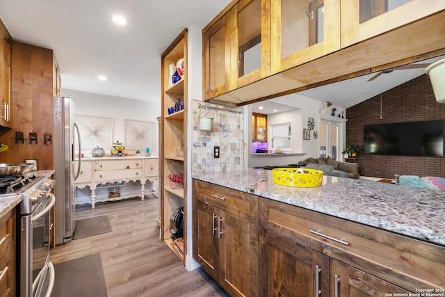 kitchen featuring ceiling fan, light stone counters, light wood-type flooring, and appliances with stainless steel finishes