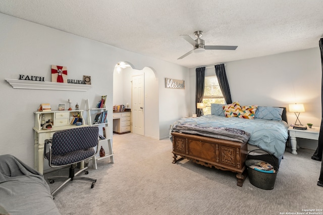 bedroom featuring ceiling fan, light carpet, and a textured ceiling