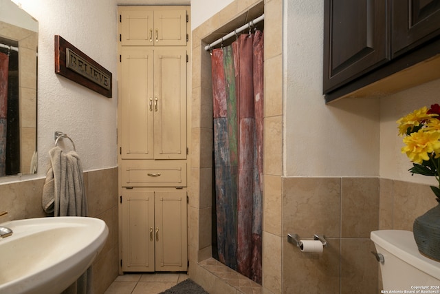 bathroom featuring a shower with shower curtain, tile patterned flooring, toilet, and tile walls