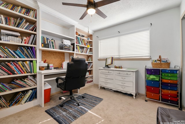 carpeted office space with a textured ceiling and ceiling fan