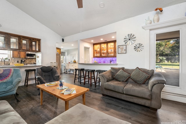 living room featuring a textured ceiling, dark hardwood / wood-style flooring, high vaulted ceiling, and indoor bar