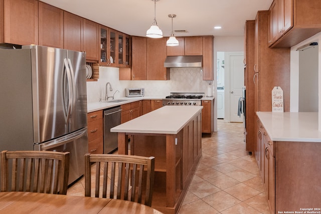 kitchen with backsplash, sink, light tile patterned floors, decorative light fixtures, and stainless steel appliances