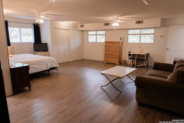 bedroom with hardwood / wood-style floors, ceiling fan, and a textured ceiling