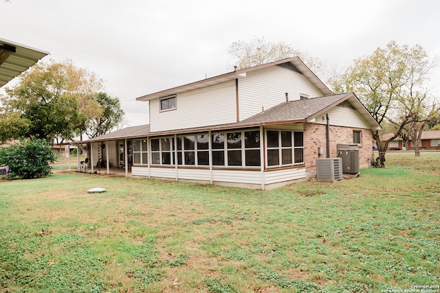 back of property with a sunroom, central AC unit, and a lawn