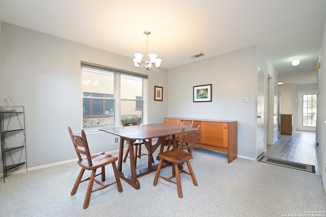 carpeted dining room with an inviting chandelier